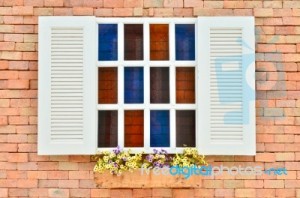 beautiful-white-wooden-window-with-colorful-flowers-on-old-brick-wall-100133341